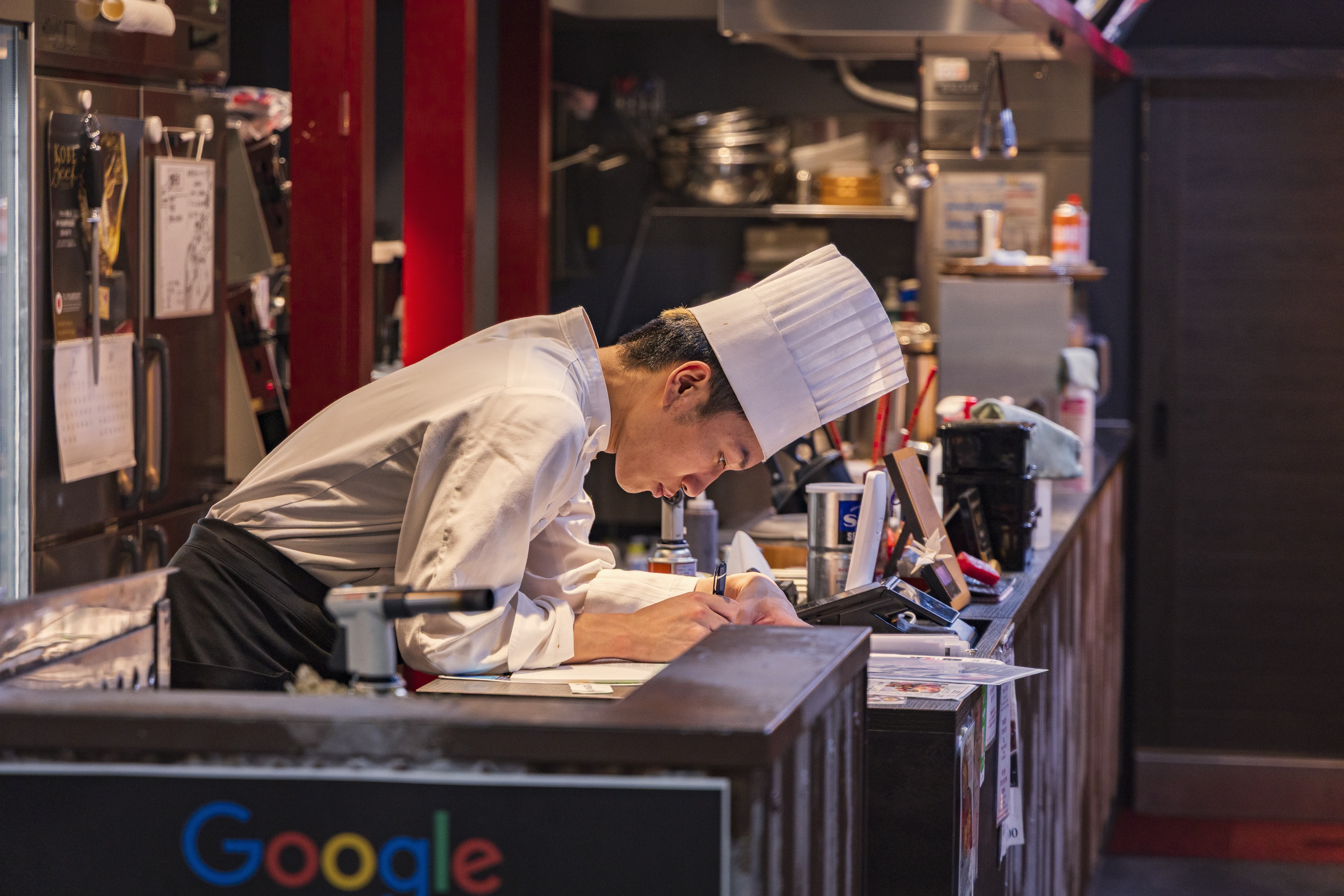 Chef writing notes in a kitchen while developing a food concept or menu